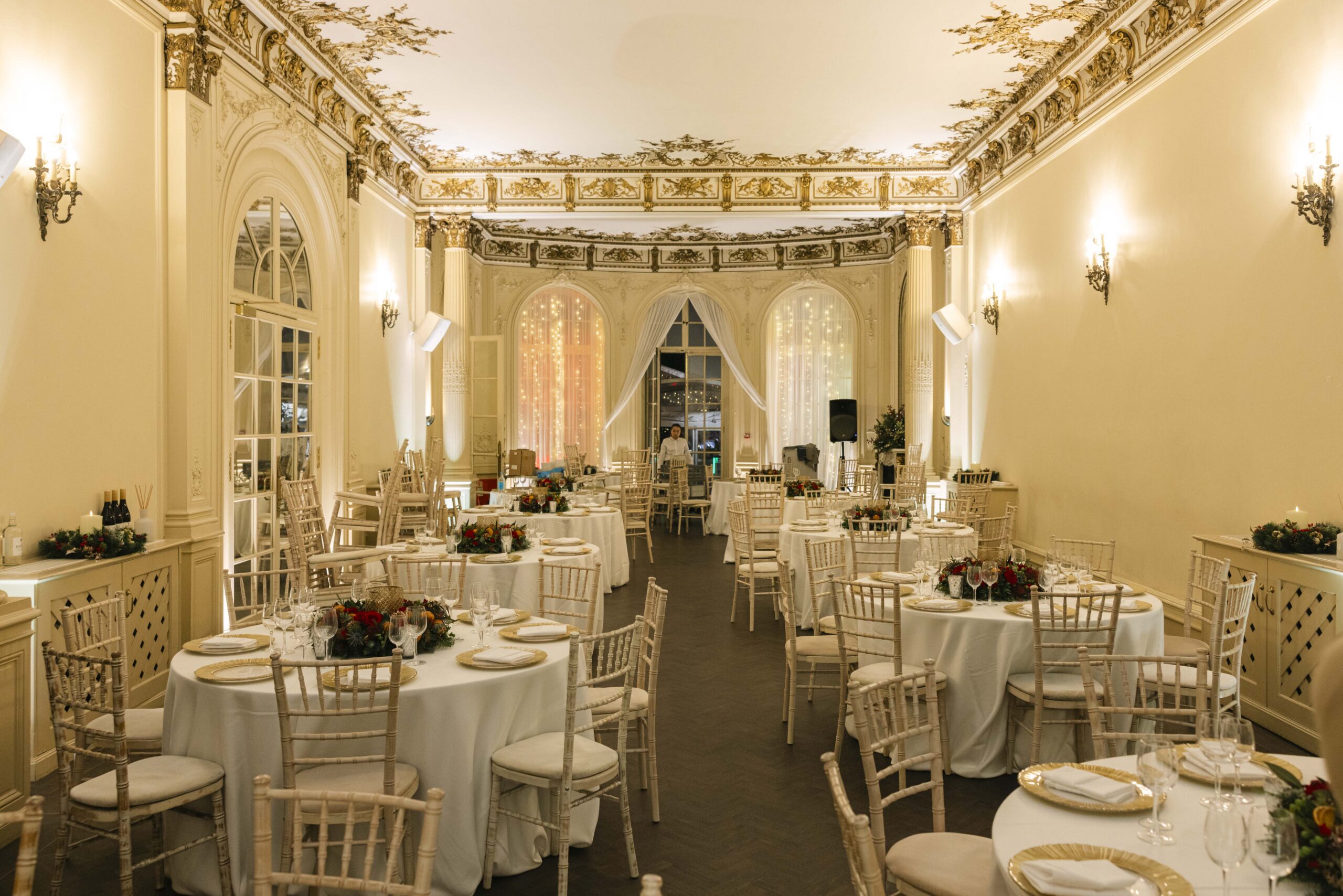 A Christmas party setup for dinner, with round tables with festive centrepieces